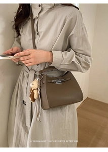 Close-up of brown litchi pattern leather bucket bag with silver twist lock and bear charm
