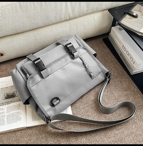 Detail of gray waterproof messenger bag with plastic buckles on a textured carpet