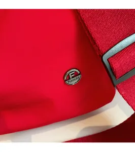 Détail du tissu en nylon rouge avec logo en métal argenté et bandoulière robuste