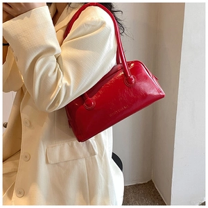 Detail of red glossy leather shoulder bag with embossed texture and thin straps