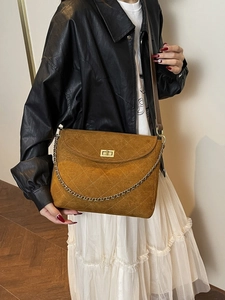 Braune Stepptasche mit Goldkette und Drehverschluss an modischem Model präsentiert