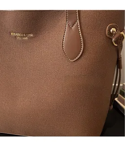 Detail of brown cross-grain leather tote bag featuring gold logo and circular metal buckle