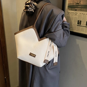 Detail of woven texture tote bag with brown trim and decorative ribbon for women