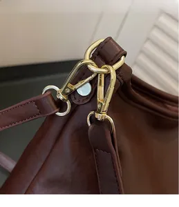 Dettaglio del gancio metallico dorato su una borsa a mano in pelle marrone elegante