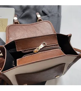 Detalle de cremallera dorada y textura de cuero en un bolso bandolera de dos tonos