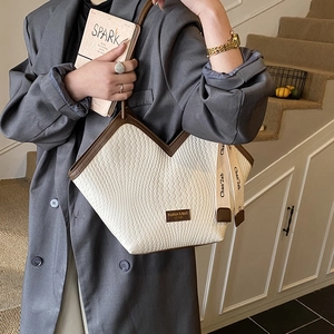 Detail of woven leather tote bag with V-shaped opening and decorative ribbon