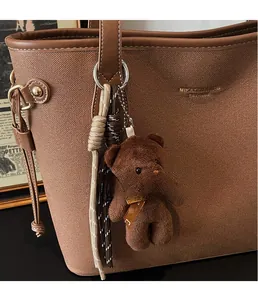 Detail of cute brown plush bear charm with woven ropes on retro leather shoulder bag