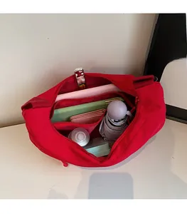 Vue intérieure du grand sac bandoulière en nylon rouge montrant les compartiments de rangement