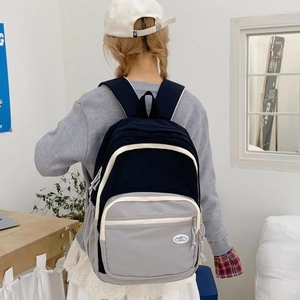 Rear view of a black and grey macaron backpack being worn by a person in a casual setting