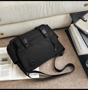 Detail view of water-resistant black nylon messenger bag with buckle closure and side pocket