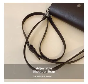 Detail view of adjustable shoulder strap on dark brown pebble leather crossbody bag