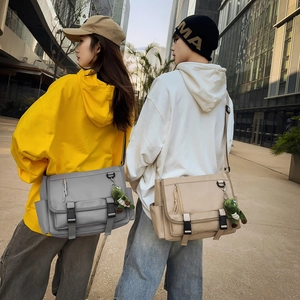 Outdoor urban view of waterproof crossbody messenger bags in gray and beige with buckle detail