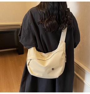 Vue détaillée d'un sac bandoulière en nylon beige avec fermeture éclair et large bandoulière