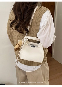 Detail of white lychee leather bucket bag with silver clasp and cute plush bear charm
