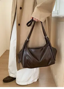 Detail of vintage dark brown faux leather hobo bag with silver buckles and adjustable strap