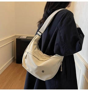 Détail du sac bandoulière en nylon crème avec une sangle large et un design épuré