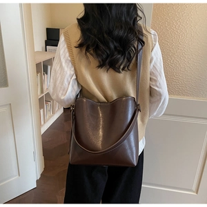 Detail of dark brown leather bucket bag showing texture and adjustable shoulder strap
