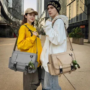 Close-up of waterproof messenger bags in grey and beige with cute frog charms
