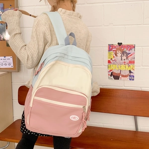 Detailed back view of pastel color-block backpack with adjustable straps on model