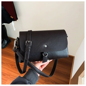 Detail of dark brown litchi pattern leather crossbody bag with silver metal hardware
