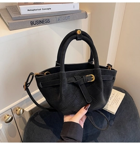 Nahaufnahme der schwarzen gesteppten Wildledertasche mit goldenen Metalldetails