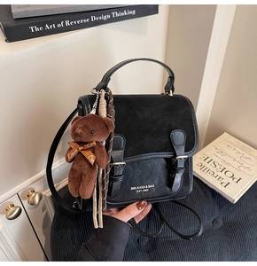 Detail of black leather and suede backpack with twin buckles and plush bear charm