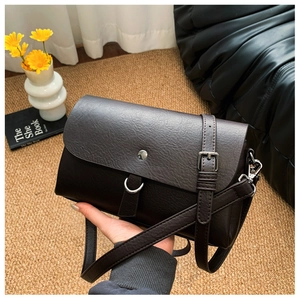 Close-up of deep brown leather crossbody bag with metal ring buckle and texture