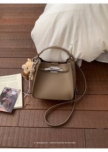 Detail of dark brown leather bucket bag with silver buckle and plush bear charm accessory