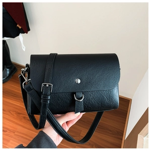 Detail of black rectangular crossbody bag with silver hardware and textured leather finish
