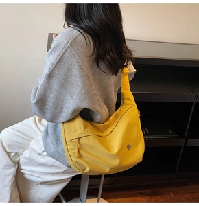 Détail du sac croissant en nylon jaune vif avec large bandoulière et logo en métal