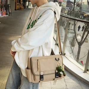 Detail view of khaki waterproof messenger bag featuring buckle closure and cute crocodile charm