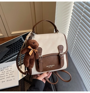 Detail of vintage beige and brown contrast backpack with buckles and plush bear charm
