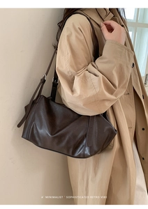 Détail de la texture d'un sac à bandoulière marron foncé avec ses lanières épurées
