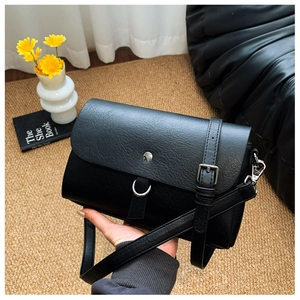 Detail of black PU leather crossbody bag featuring silver metal buckle and adjustable strap