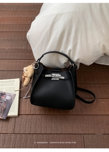 Detail of black pebbled leather bucket bag with silver lock and plush bear charm decoration