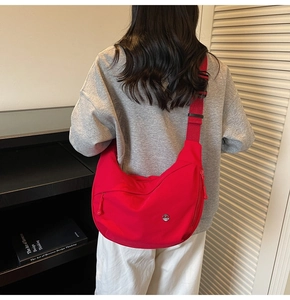 Détail du sac bandoulière croissant en nylon rouge avec large sangle réglable contrastée