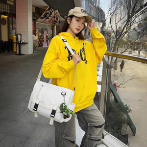 Detailed view of a white large capacity messenger bag with black buckles and green dino charm