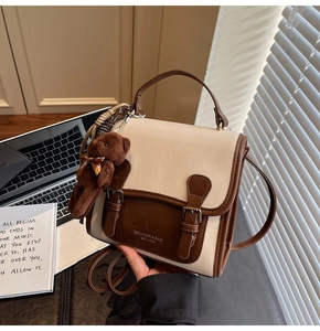 Detail of vintage beige and brown contrast backpack with cute plush bear charm