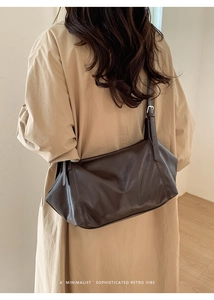 Détail d'un sac à bandoulière marron foncé minimaliste porté avec un trench-coat classique