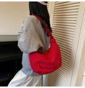 Détail d'un grand sac croissant en nylon rouge avec bandoulière réglable sur un mannequin
