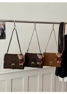 Close-up of retro crossbody bags in brown tones with gold hardware and bear charm