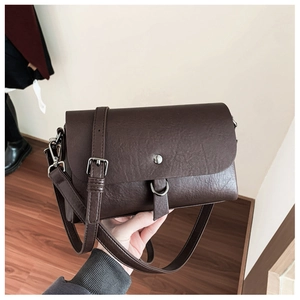 Detail of vintage dark brown square crossbody bag with metallic clasp and adjustable strap