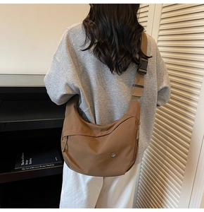 Détail du sac bandoulière demi-lune en nylon kaki avec large sangle et logo en métal
