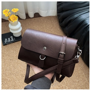 Close-up of brown lychee texture leather handbag with silver clasp and adjustable strap