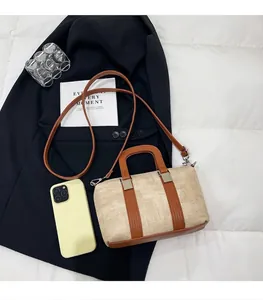 Top view of beige woven boston bag with brown leather accents on a black blazer jacket