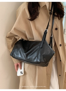 Close-up of a black minimalist faux leather tote bag with an adjustable shoulder strap