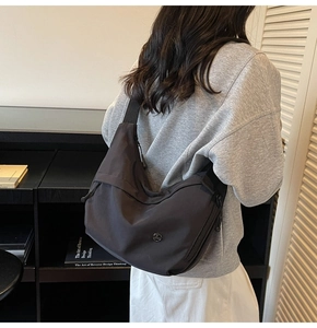 Vue de dos d'un mannequin portant un sac hobo en nylon noir avec bandoulière réglable