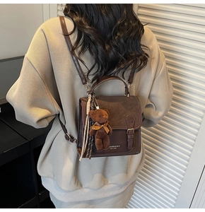 Detail of vintage brown leather backpack with strap buckle, bear charm and silk scarf