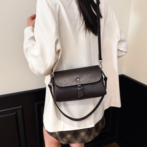Detailed texture of dark brown retro leather shoulder bag with metallic buckle closure