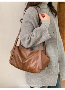 Close-up of caramel brown leather shoulder bag with vintage pleated texture and side buckle